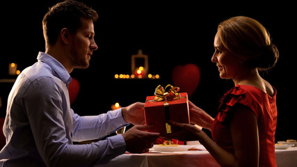 Beautiful woman giving red gift box to surprised beloved man, be my valentine