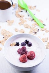 BOL CON YOGUR Y FRESAS Y ARÁNDANOS RODEADO DE CEREALES INTEGRALES Y TAZA DE CAFÉ