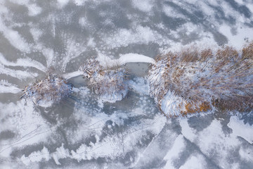 Aerial view of the winter snow covered forest and frozen lake from above captured with a drone.