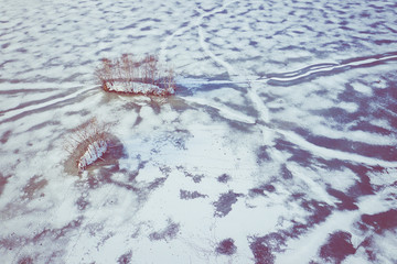 Aerial view of the winter snow covered forest and frozen lake from above captured with a drone.