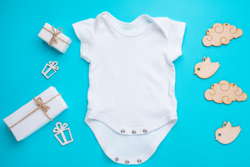 mockup Flat Lay a white children's shirt with wooden toys and gifts on a blue background. Layout...