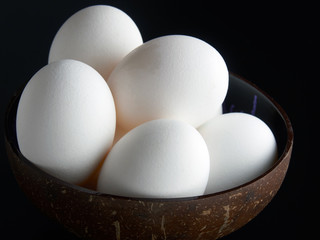 Fresh eggs in the bowl on the black background