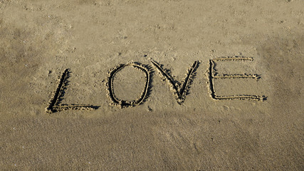 Love word written in sand on wet sandy beach. New summer is coming, holiday vacation travel day time concept. I love summer and need holiday message on coast. Copy space for ad banner.