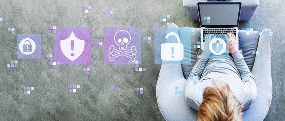 Virus and scam theme with man using a laptop in a modern gray chair