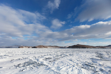 Fototapeta na wymiar Lake Baikal winter landscape. Mountain shore in the distance