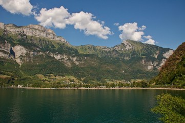 Naklejka na ściany i meble Walensee ( Schweizer See ) im Hintergrund die Berge Churfirsten: Frümsel, Hinterrugg, Brisi,. im Hintergrund der Campingplatz von Walenstadt.