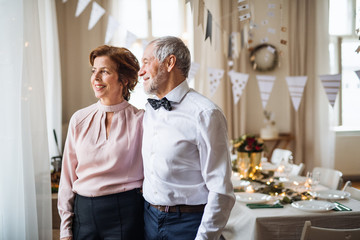 Senior couple standing indoors in a room set for a party. Copy space.