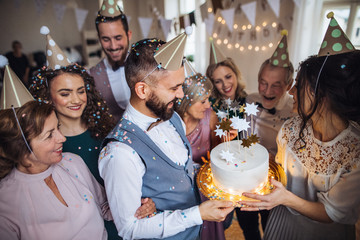 A portrait of multigeneration family with a cake on a indoor birthday party.