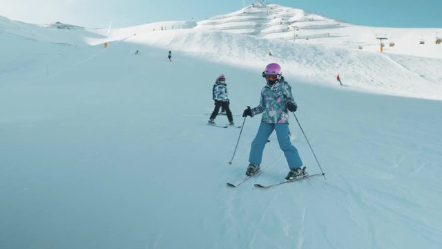 Group of junior skiers practising down hill ski slopes. Large Italian mountain range in background.
