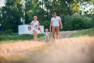 Naklejka na ściany i meble Young family with a small toddler boy in sunny summer nature.