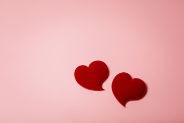 Two red velvet hearts in soft focus on a pink background. Background with copy space for Valentine's day or wedding