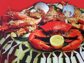 The fine choice of sea delicacies for dinner. A lobster, a crab with a lemon, huge shrimps and mussels on a dish.