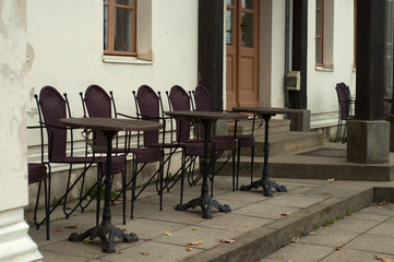 Restaurant tables and chairs against the background of the wall of the white house. Exquisite and cozy interior. Shallow depth of field, daylight shooting