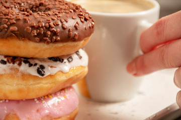 three donuts on a white tray with a cup of coffee
