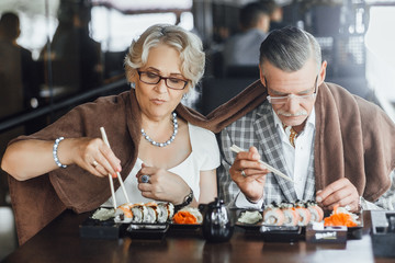 Beautiful mature couple eating sushi in cafe ,summer terrace,nice day