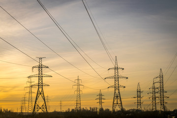 electric pylons with wires going into the distance at dawn or dusk. 