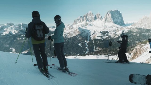 Wide shot of skiers waiting at the top of the hill with a gorgeous mountain range in the background.