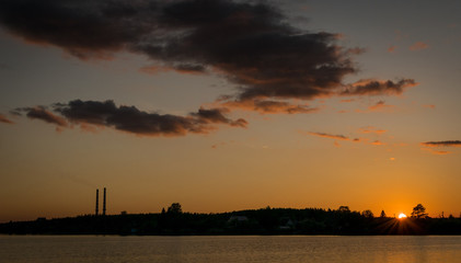 Fototapeta na wymiar sunset or sunrise next to a reservoir with an industrial factory and chimneys. 