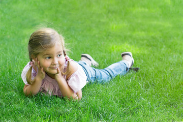 girl with pigtails lying on the green grass