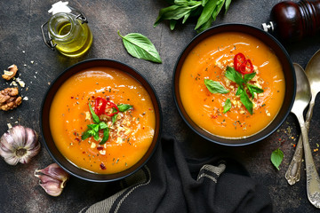 Two portions of homemade pumpkin carrot soup with walnuts in a black bowls.Top view with copy space.