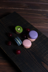 Colorful macaroons lie on a wooden background. Menu design, place for text.