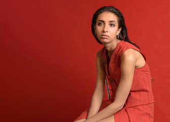 Beautiful woman in red dress with wet style hair on red background. Tired girl. Copy space
