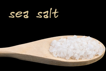 sea salt on wooden spoon isolated on black background