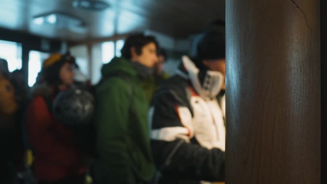 Blurred out focus on groups of skiers waiting in queue. Focal point wood frame of entrance.