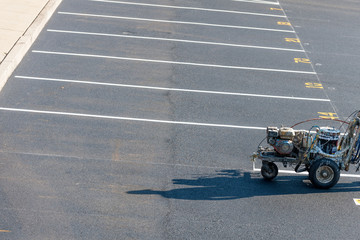 Worker with a striping mashing painting fresh lines in development parking lot, USA