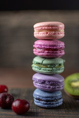 Beautiful and tasty French macaroon cookies stand on a wooden stand next to the fruit. Romantic dinner in the back of the house. Fast food menu background.