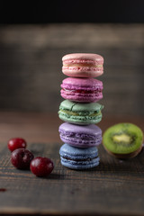 Beautiful and tasty French macaroon cookies stand on a wooden stand next to the fruit. Romantic dinner in the back of the house. Fast food menu background.