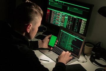 Hacker using laptop and smart phone in the dark