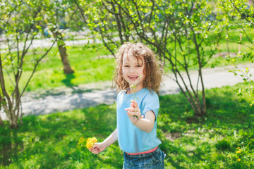 The girl gives her mother a dandelion flower. Happy baby on a walk. Widely smiling beautiful girl on a background of grass and bushes in spring. Mothers Day. Women's Day. March 8