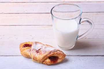 Breakfast with traditional hot cross bun with jam and glass with milk on wooden table. Top View