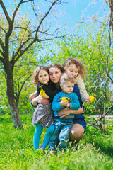 Fototapeta premium Mom with three children - boy and two girls smiling, and her children are hugging. Happy large family in nature.
