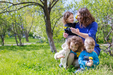 Fototapeta premium Mom with three children - boy and two girls smiling, and her children are hugging. Happy large family in nature.