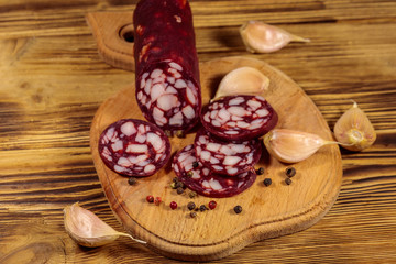 Sliced salami sausage on cutting board on wooden table