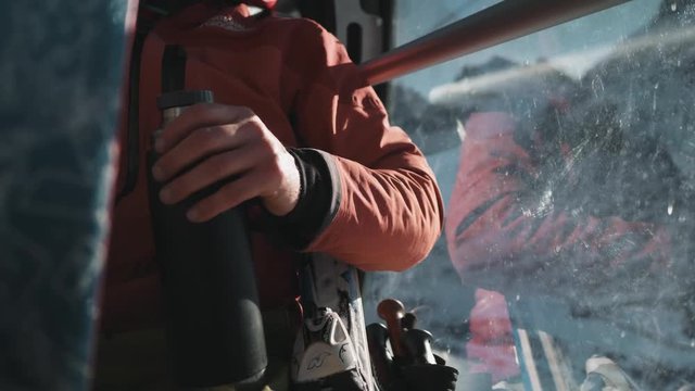 CLOSE UP of a man in a gondola trying to open a thermos.