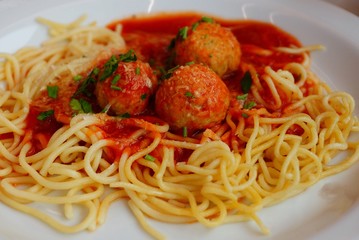 spaghetti with red sauce and round meatballs on a white plate