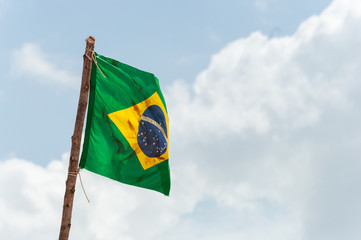 Brazilian flag is waving at a beautiful and peaceful blue sky at Amazonas river.