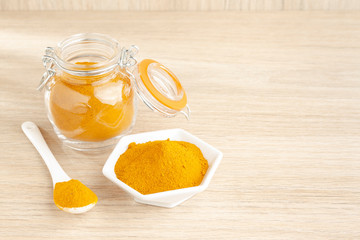 turmeric powder in glass bowl on wood