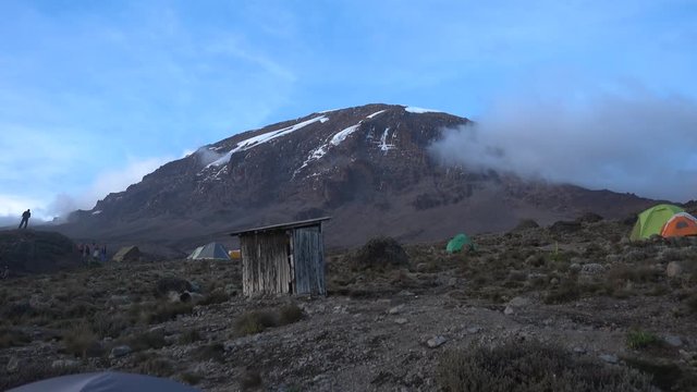 Wide Shot of Summit of Mount Kilimanjaro. Blue Sky and Small Cloud. With Tents and People Standing