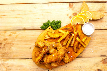 Fish and chips on wooden board and table. Traditional British food, top view.