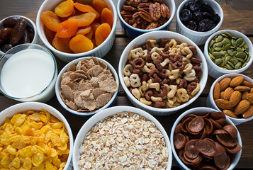 various cereals, nuts and dried fruits on wooden surface