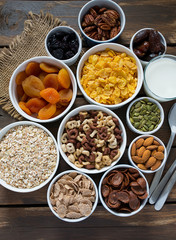 various cereals, nuts and dried fruits on wooden surface