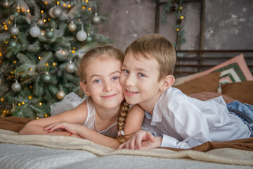 Sister and brother lying on sofa under Christmas tree