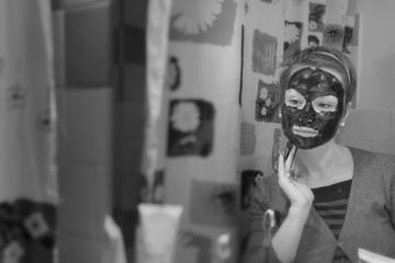 Young woman with black  cosmetic mask on her face