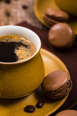 Coffee Cup, Beans and Dark Chocolate Macarons Cookie on Wooden Table. Selective focus. 