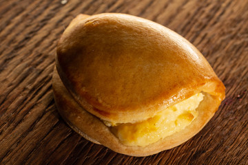 Sweet bun with cheese, juicy, on a brown oak background
