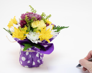 Bouquet of Flowers wrapped in purple polka dot wrap with a hand writing a note